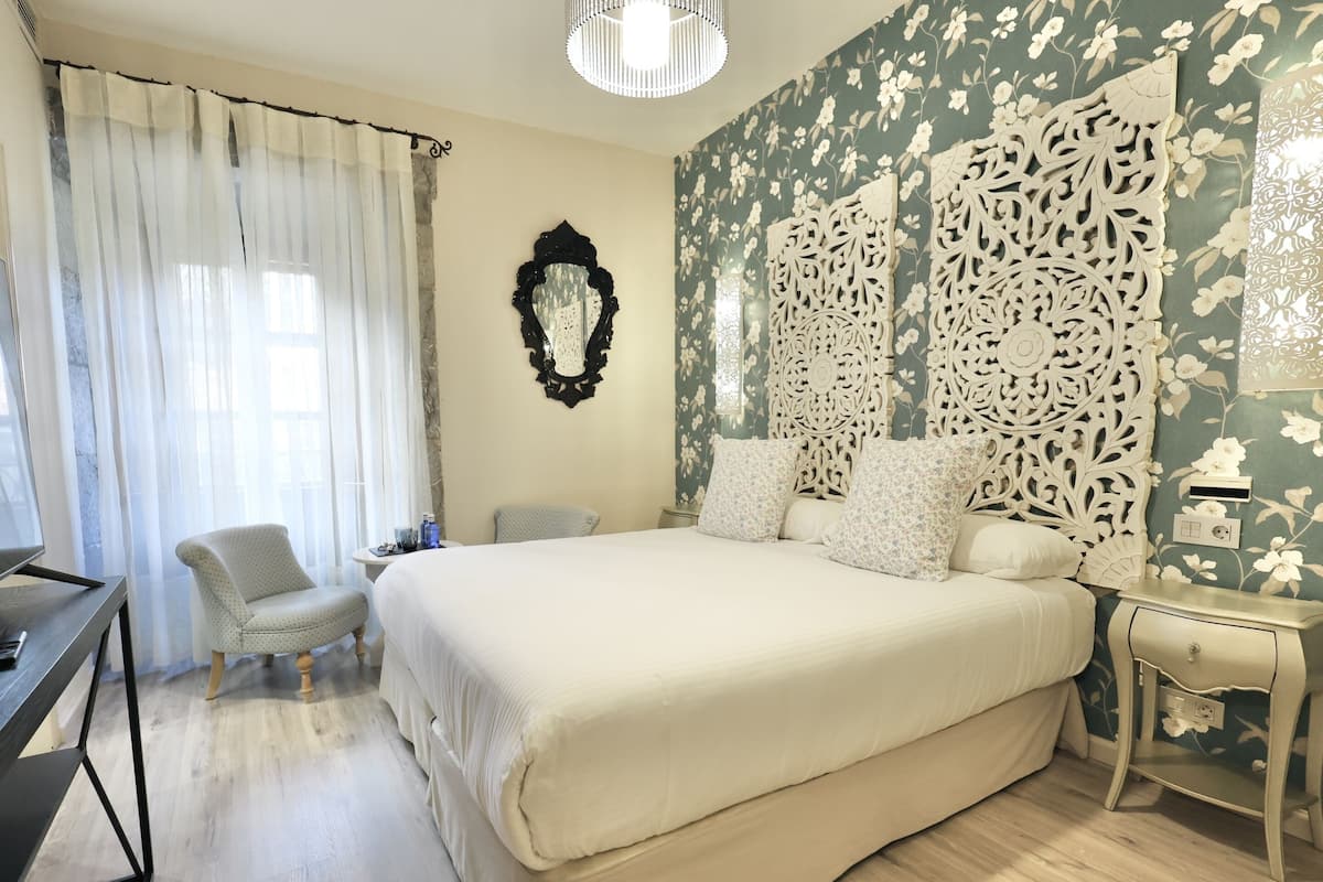 A bedroom with a large bed, a desk, a chair, and a decorative wall panel.