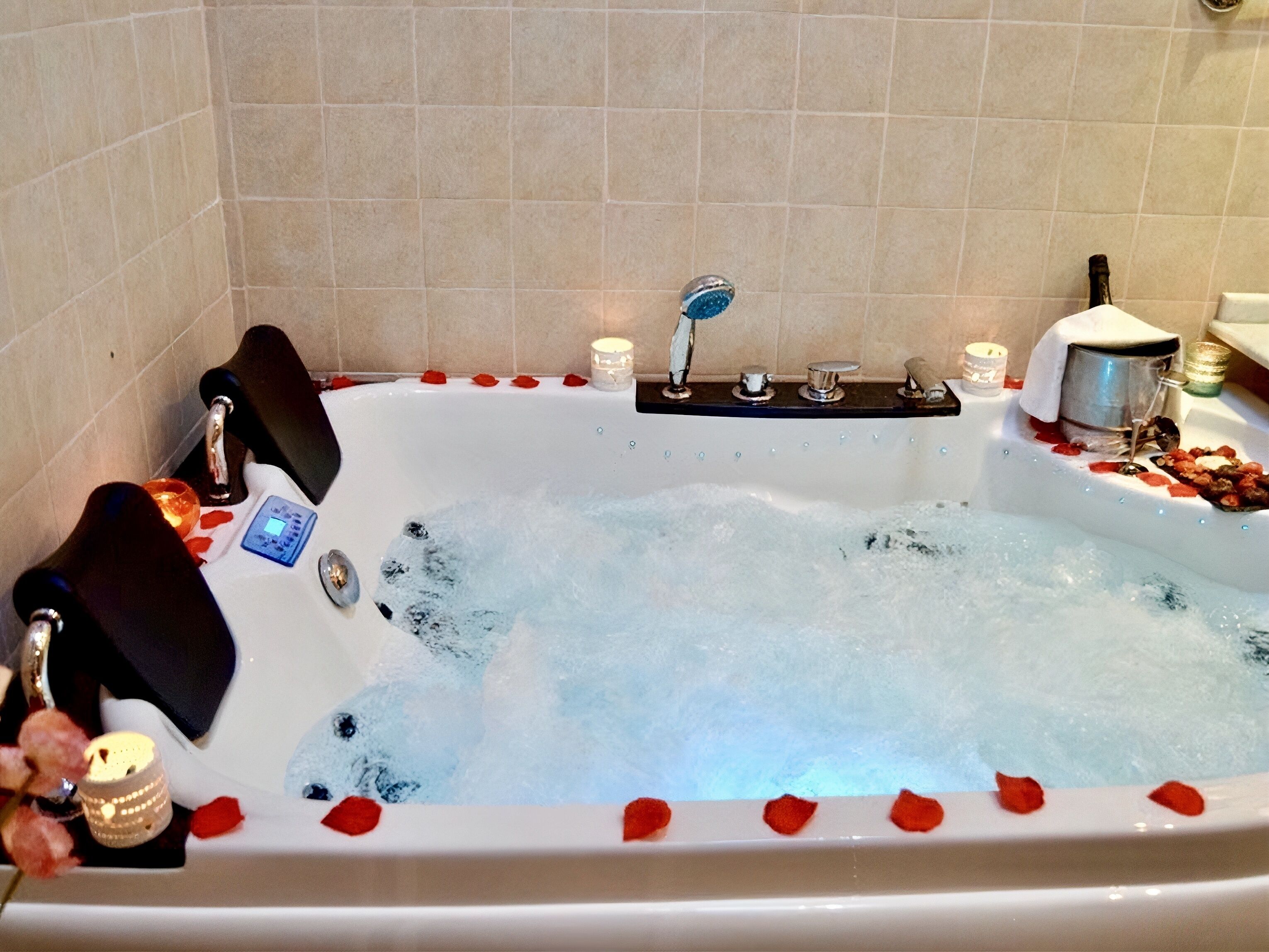 Una bañera llena de agua, rodeada de pétalos de rosa, con un panel de control y velas.