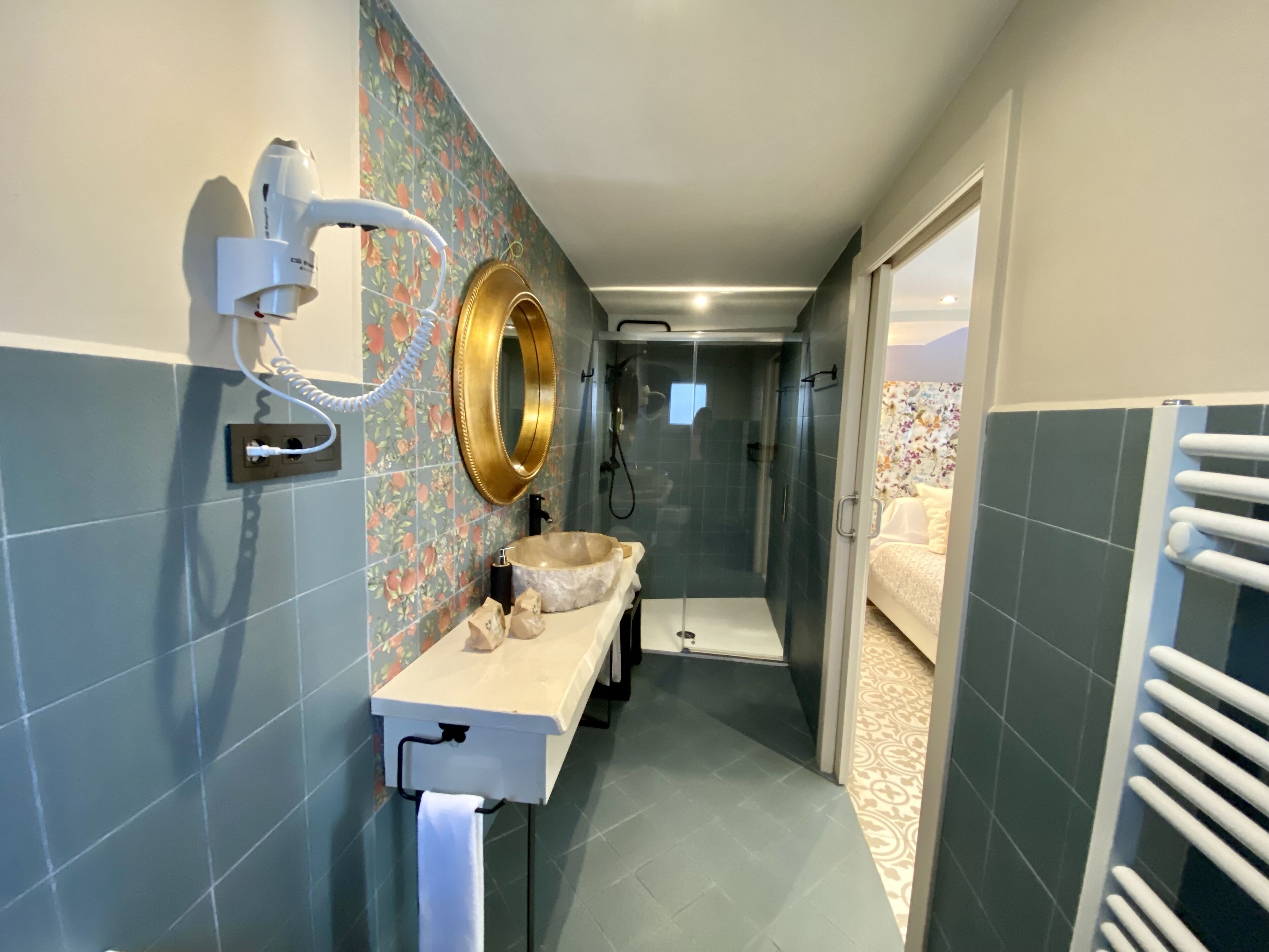 A modern bathroom with a shower, a sink with a gold-rimmed mirror, and a toilet.