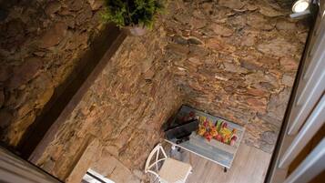 Una habitación con paredes de piedra, una mesa de madera y sillas, una planta en maceta y un ventanal.