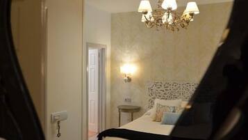 Una habitación de hotel con una cama, un candelabro, una lámpara de pared y una puerta.