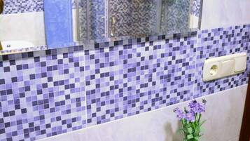 Un bagno con rivestimento in piastrelle, un lavandino bianco, uno specchio e un box doccia.