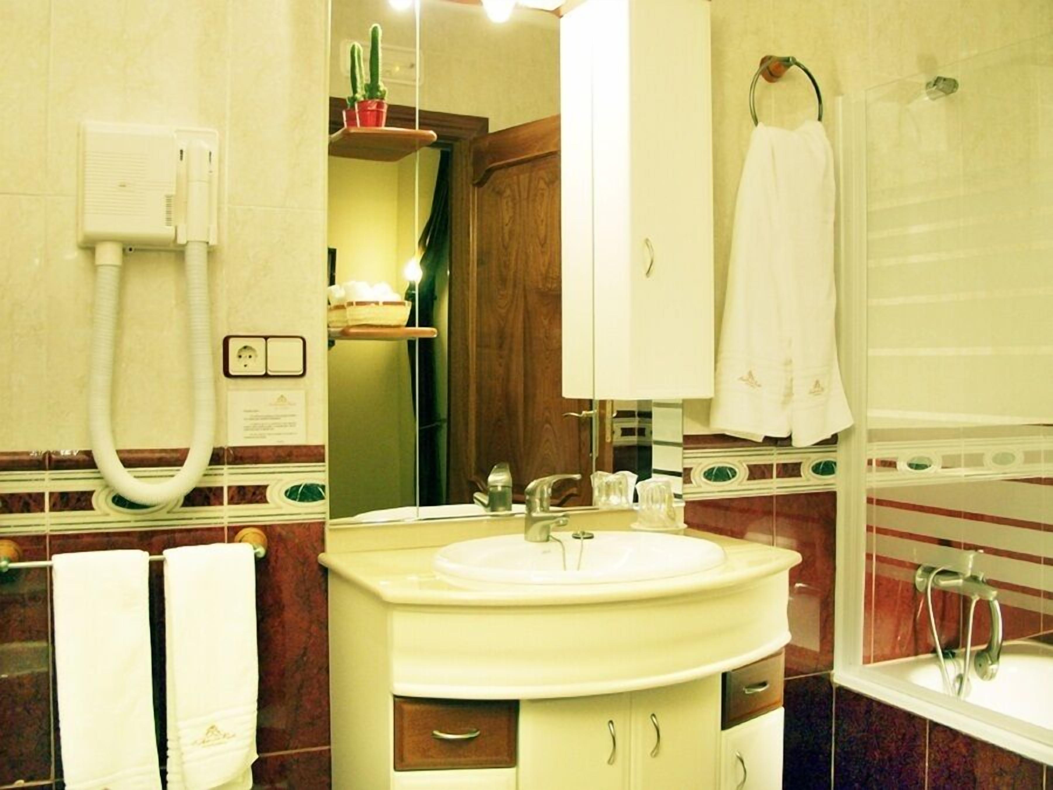 Un baño con lavamanos, espejo, toallero, ducha y calefactor.