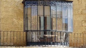 A stone building with a large, ornate window with metal bars and a balcony. - Palacio Antigua Audiencia (Ciudad Rodrigo)