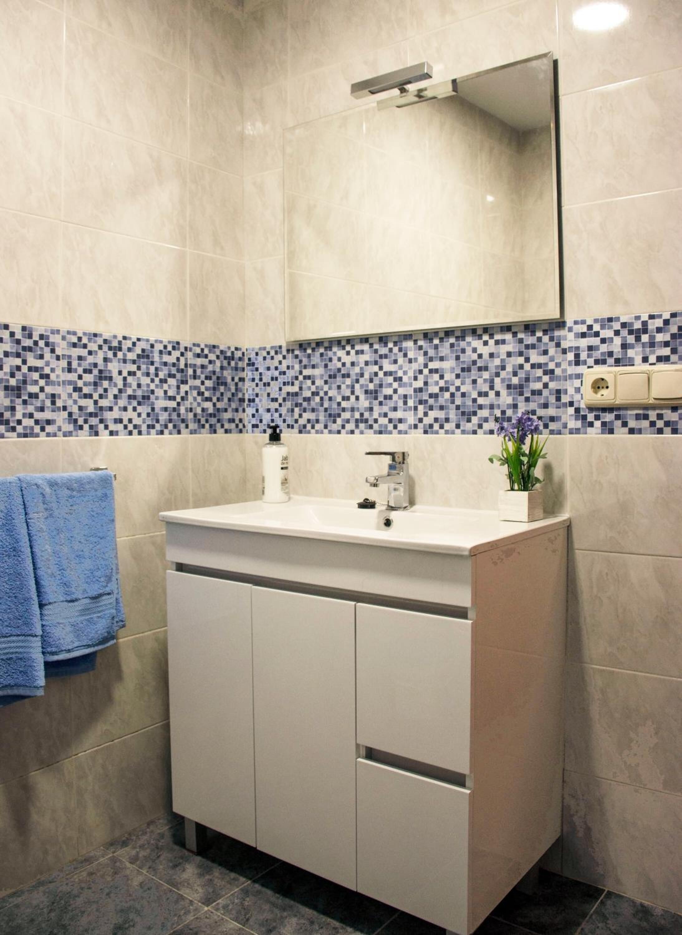 A bathroom with a white vanity, a mirror above the sink, and a tiled backsplash.