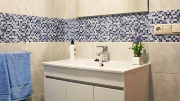 A bathroom with a white vanity, a mirror above the sink, and a tiled backsplash.