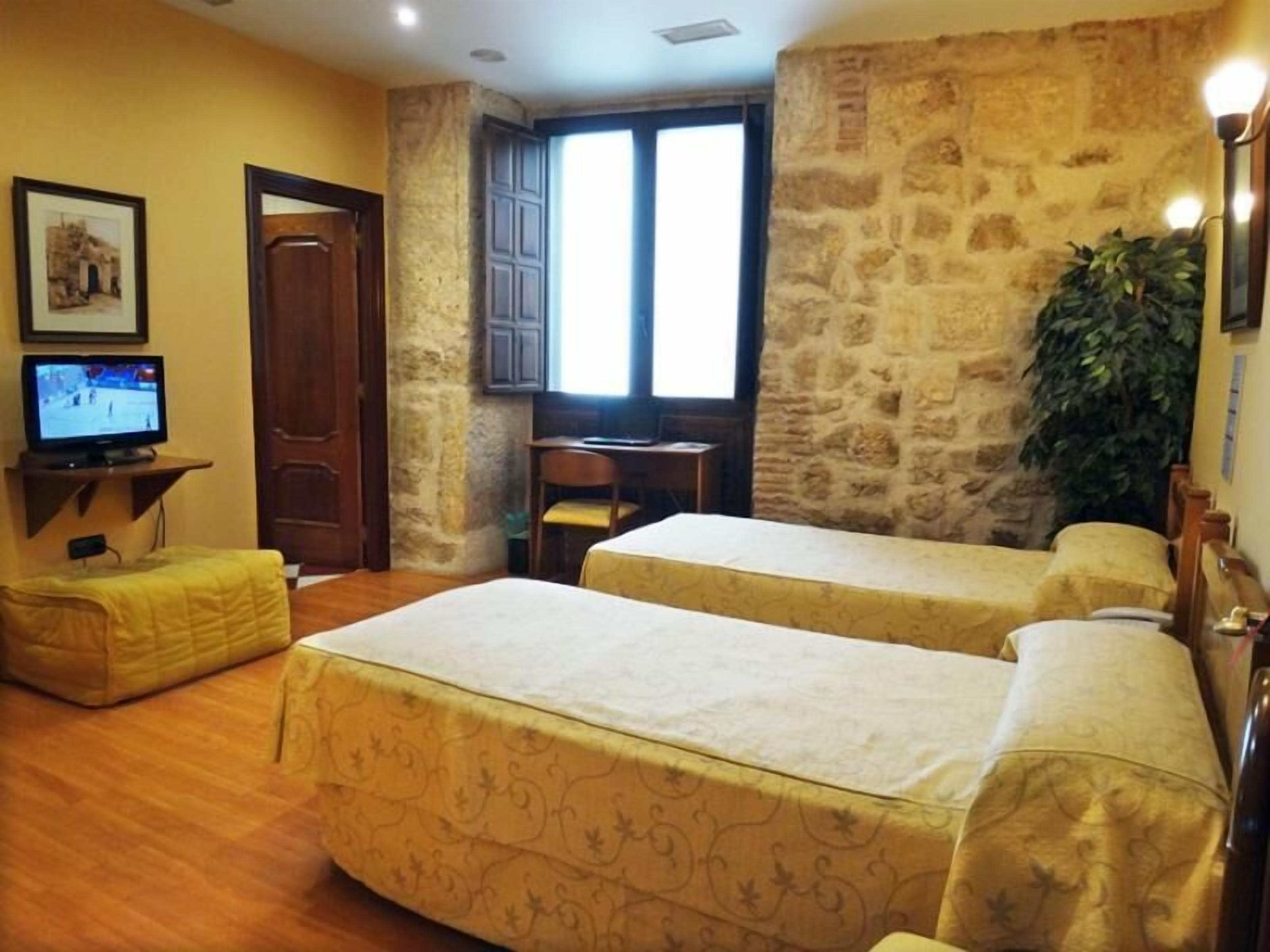 Una habitación con dos camas, un escritorio, una televisión y una ventana que ofrece vistas al exterior.