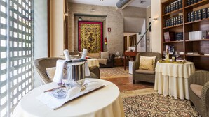 Una habitación de hotel acogedora con zona de comedor, una estantería y un tapete estampado.