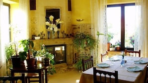A dining area with a fireplace, potted plants, and a table set for dining. - La Casa del Filandón (Luyego)