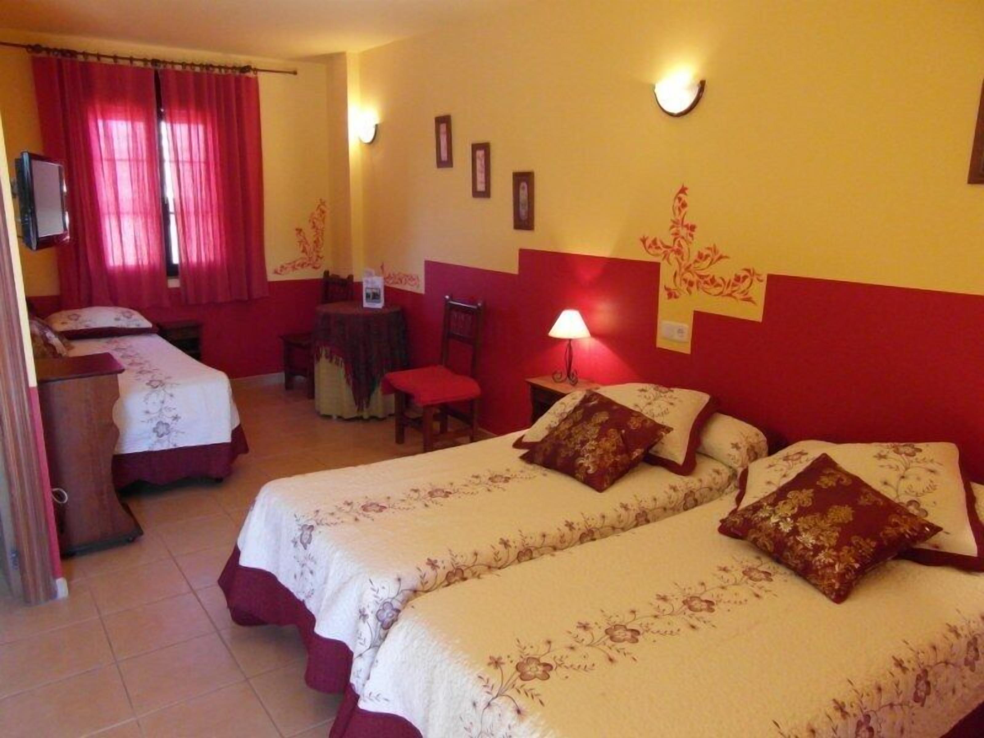 Habitación de hotel con dos camas, un escritorio, una silla y una lámpara.