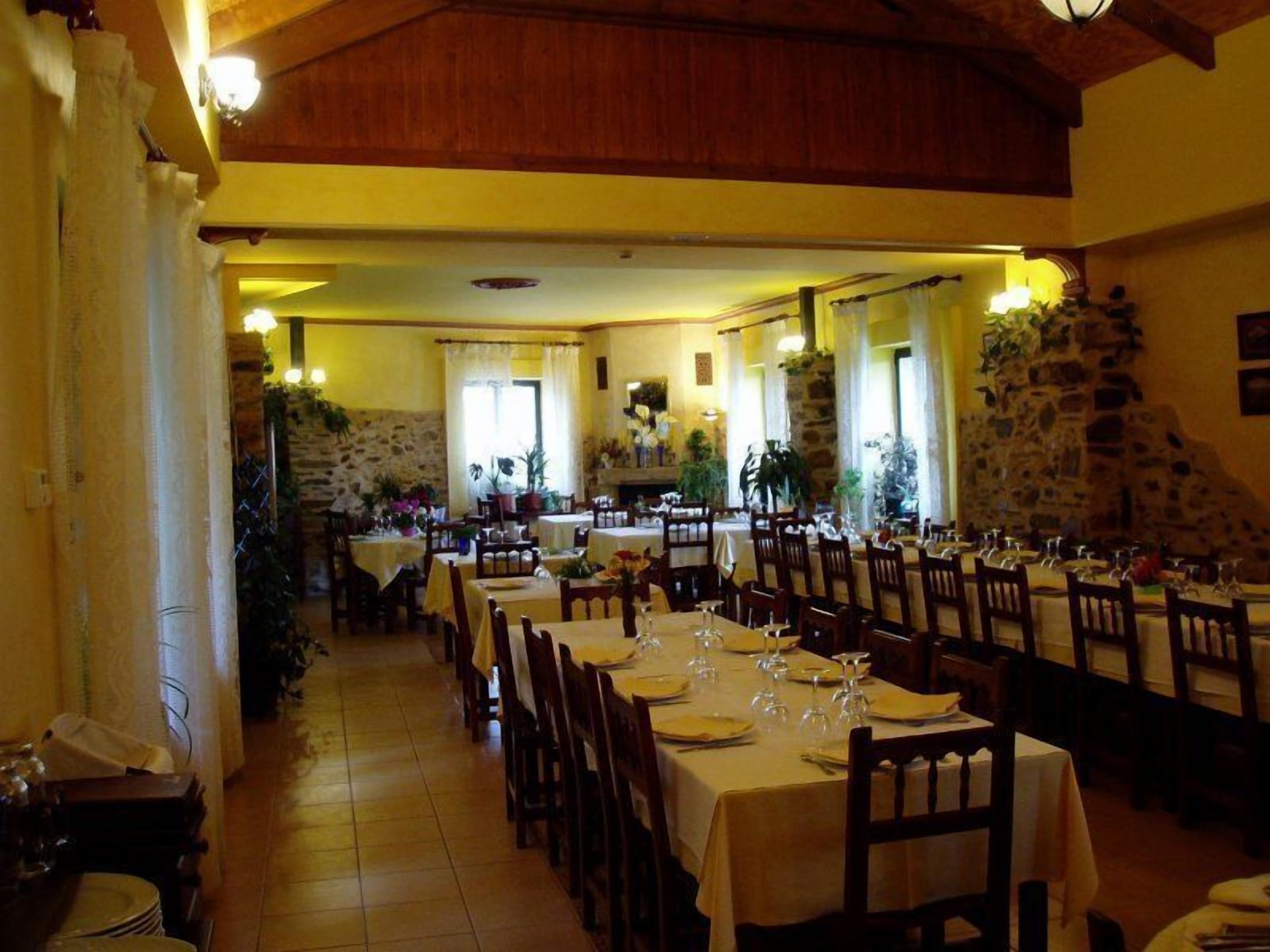 Een restaurant met meerdere tafels, stenen muren en potplanten.