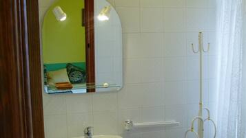 A bathroom with a sink, mirror, and shower.