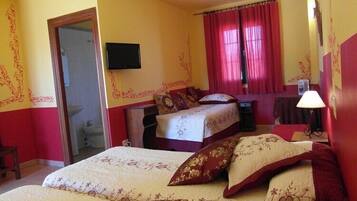 A hotel room with a bed, a desk, a chair, a television, and a window with curtains.