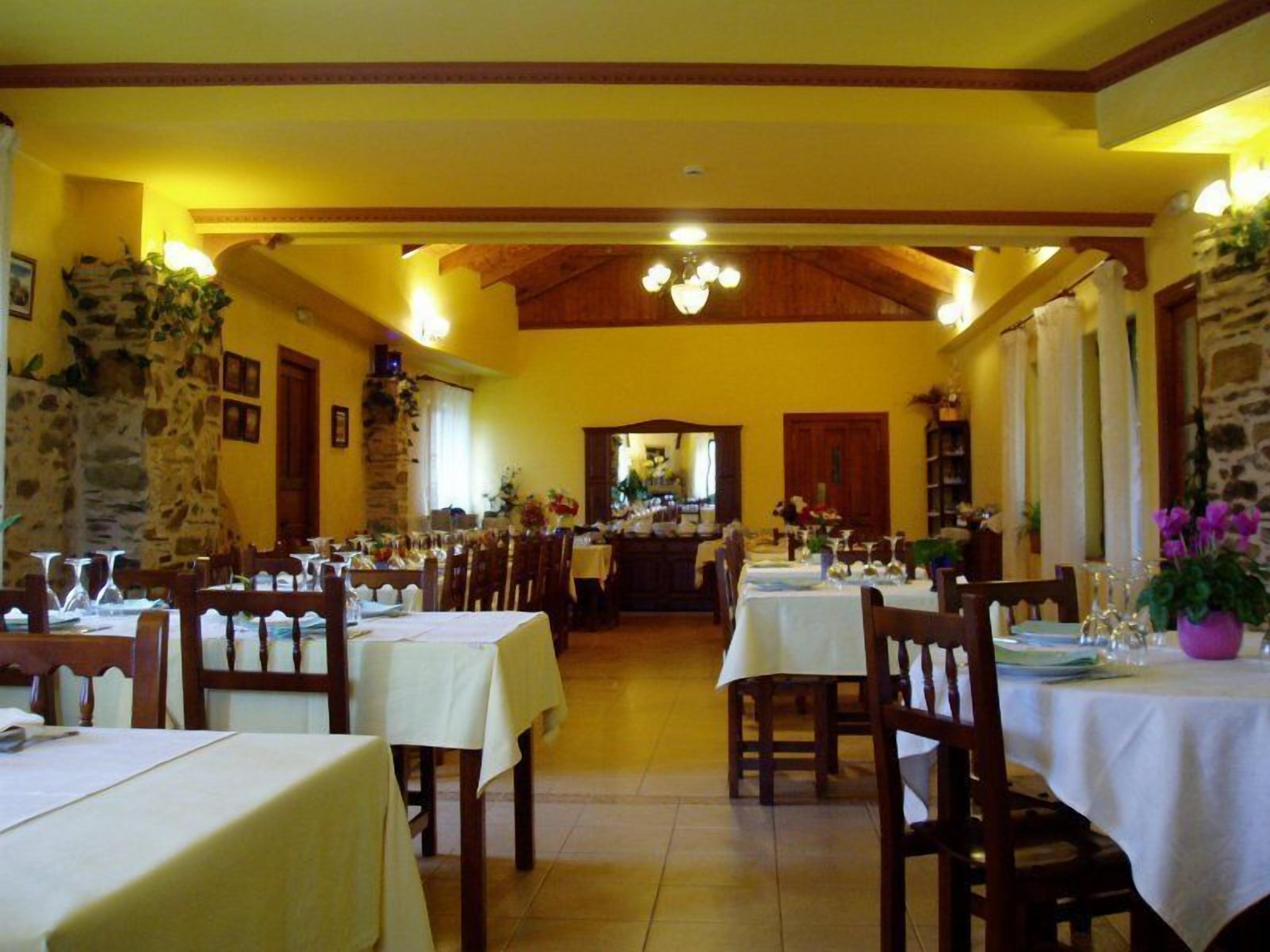 Un restaurante con varias mesas, sillas de madera y una pared de piedra.