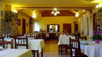 Un restaurante con varias mesas, sillas de madera y una pared de piedra.