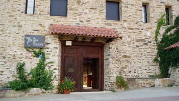 Un edificio de piedra con tejado de tejas, una puerta de madera y un letrero que dice "La Casa del Vino".