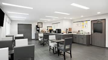 Una cucina moderna con zona pranzo, dotata di macchina da caffè, forno a microonde e frigorifero.