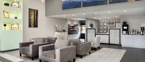 A hotel lobby with a seating area, a reception desk, and framed artwork on the walls.
