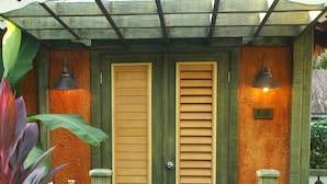 A wooden gate with a number '515' sign, a wooden door with horizontal slats, and a small light fixture above the door.