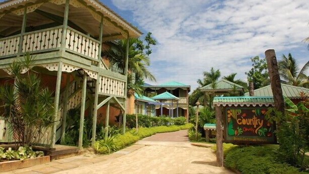 A resort with a covered outdoor area, a pathway leading to the main building, and a sign indicating 'Country Cottage'.