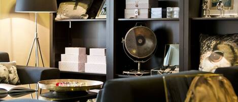 Una sala de estar moderna con un sofá, una mesa de centro, una lámpara y una estantería llena de objetos decorativos y libros.