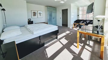 A hotel room with a bed, a desk, a TV, and a wardrobe.