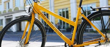 A yellow bicycle parked in front of a building with a sign that reads "Velle Center Hotel".