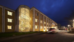 A modern hotel with a curved glass facade and multiple windows. - Milling Hotel Vejle (Vejle)