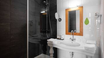 A modern bathroom with a glass-enclosed shower, a white sink with a wooden frame mirror, and a white toilet.