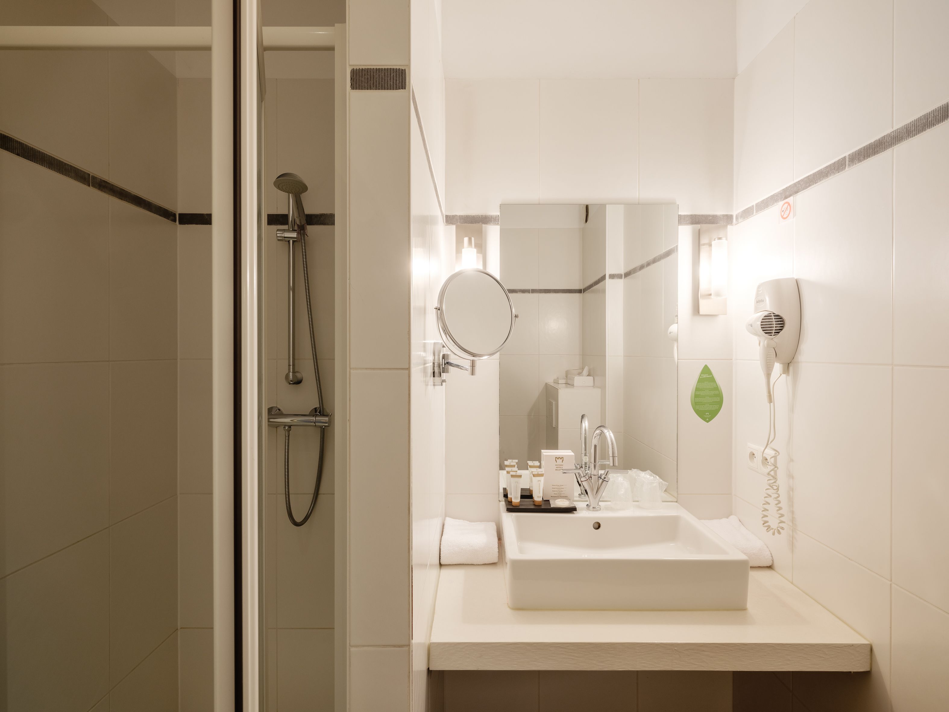 A modern bathroom with a shower, sink, and hairdryer.