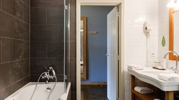 A modern bathroom with a bathtub, a shower, and a vanity with a sink and towel rack.