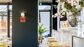 Zona de buffet con diversas opciones de comida, un cartel de prohibido fumar y un arreglo floral.