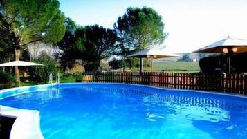 Een buitenzwembad, parasols bij het zwembad en ligstoelen