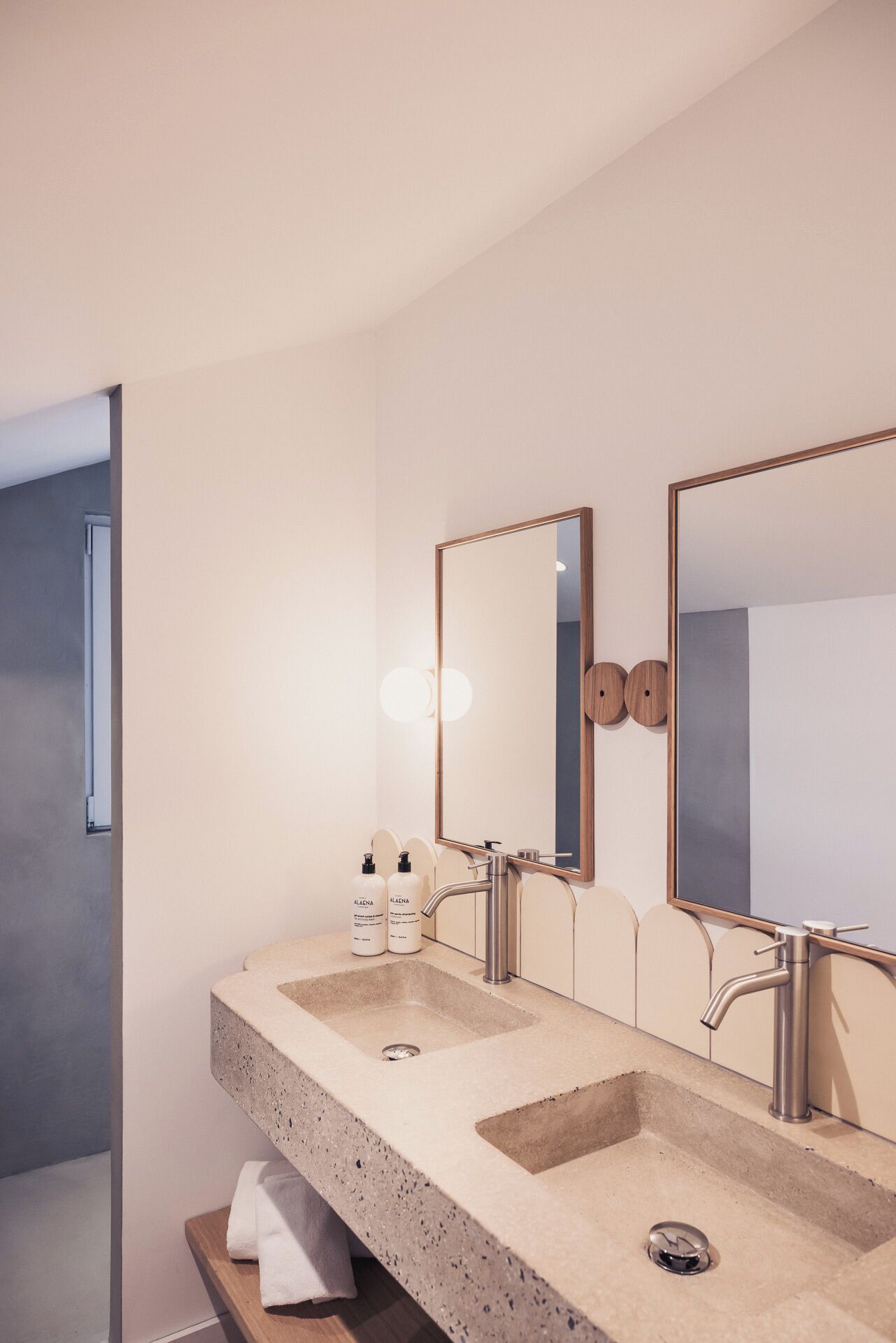 A modern bathroom with two sinks, a large mirror, and a towel rack.