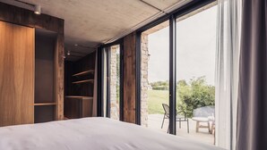 Un dormitorio con un ventanal grande, un armario de madera y vistas al exterior.