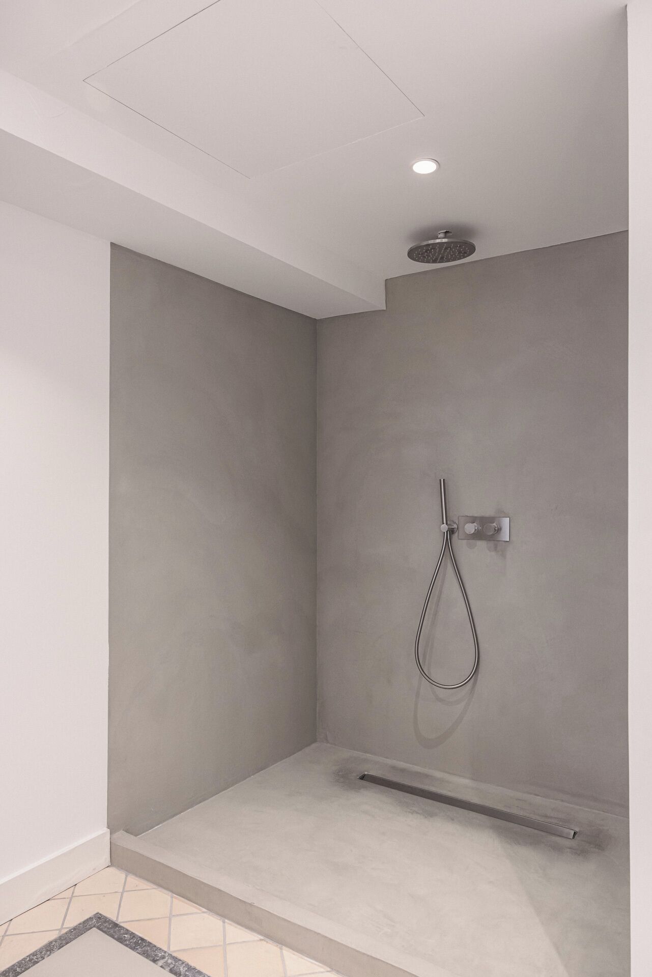 Een moderne douche met een handdouche en een bedieningspaneel op de muur.
