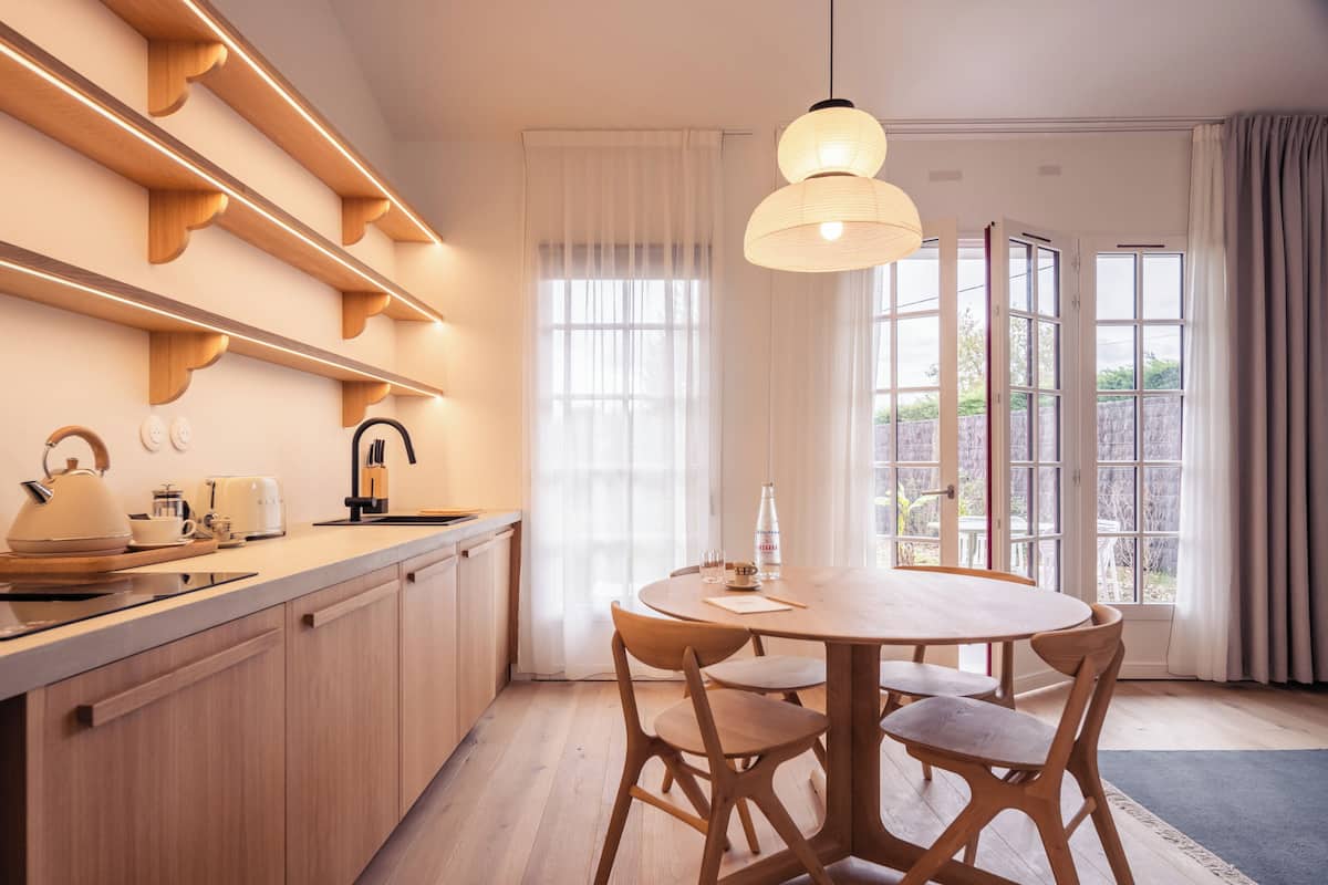 Une cuisine moderne avec des meubles en bois, une table de salle à manger ronde et des luminaires suspendus.