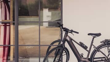 Un vélo est garé devant un bâtiment dont le toit est recouvert de tuiles et qui possède une porte en verre.