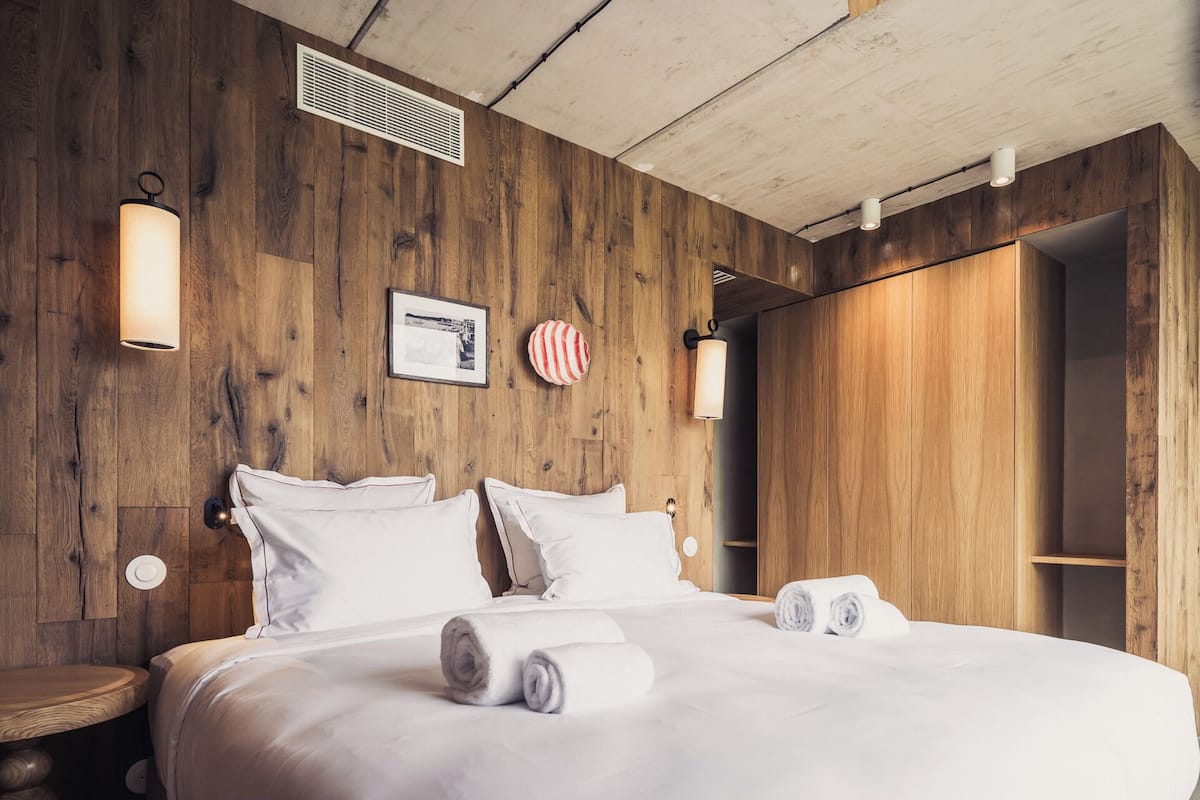 Une chambre d’hôtel avec un mur en bois, un lit recouvert de draps blancs et un cadre photo.