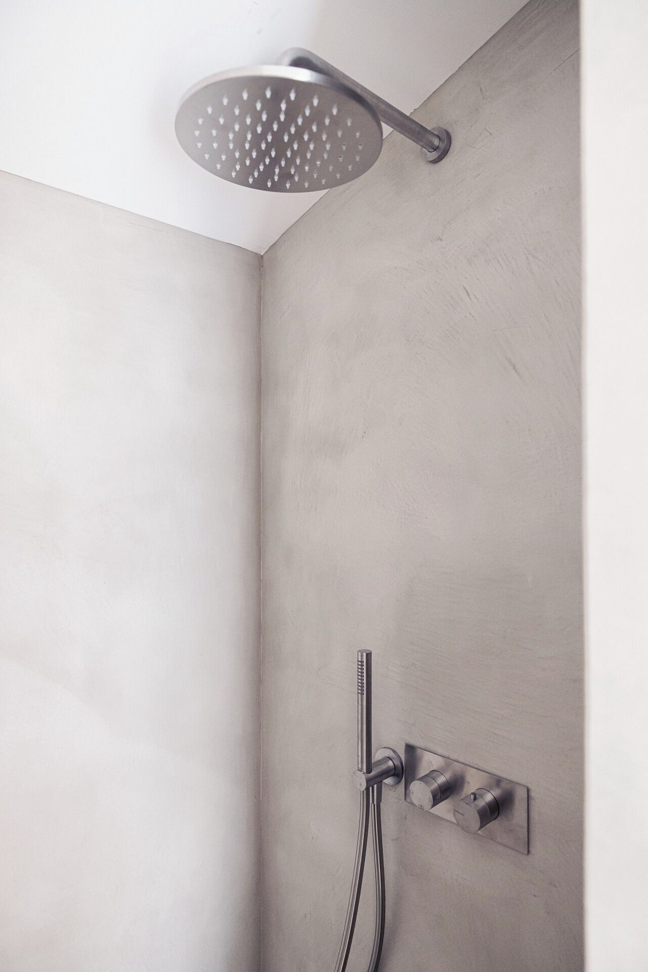 Une douche équipée d’un pommeau de douche à effet pluie et d’un pommeau de douche portatif.