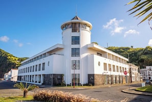 Un hotel moderno con una torre central, múltiples ventanales y un cielo despejado.