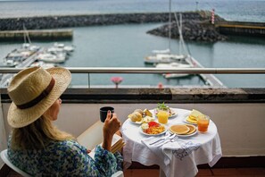 A person seated at a table with a meal, overlooking a marina with boats. - Hotel do Mar (Povoacao)