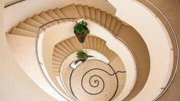 A spiral staircase with beige steps and a circular mosaic floor.