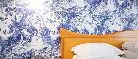 A hotel room with a wooden headboard, white bedding, and a nightstand with a telephone.