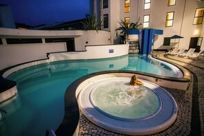 A swimming pool with a hot tub, lounge chairs, and a building in the background. - Hotel do Mar (Povoacao)