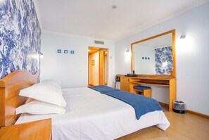 A hotel room with a bed, a desk, a mirror, and a door leading to another room. - Hotel do Mar (Povoacao)