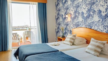 Een hotelkamer met een bed, een nachtkastje, een raam met gordijnen en uitzicht op het omliggende landschap.