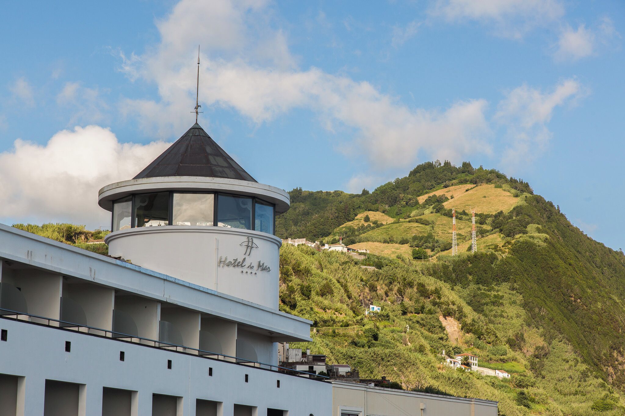 Un hôtel doté d’une tour imposante et offrant une vue sur une colline verdoyante.