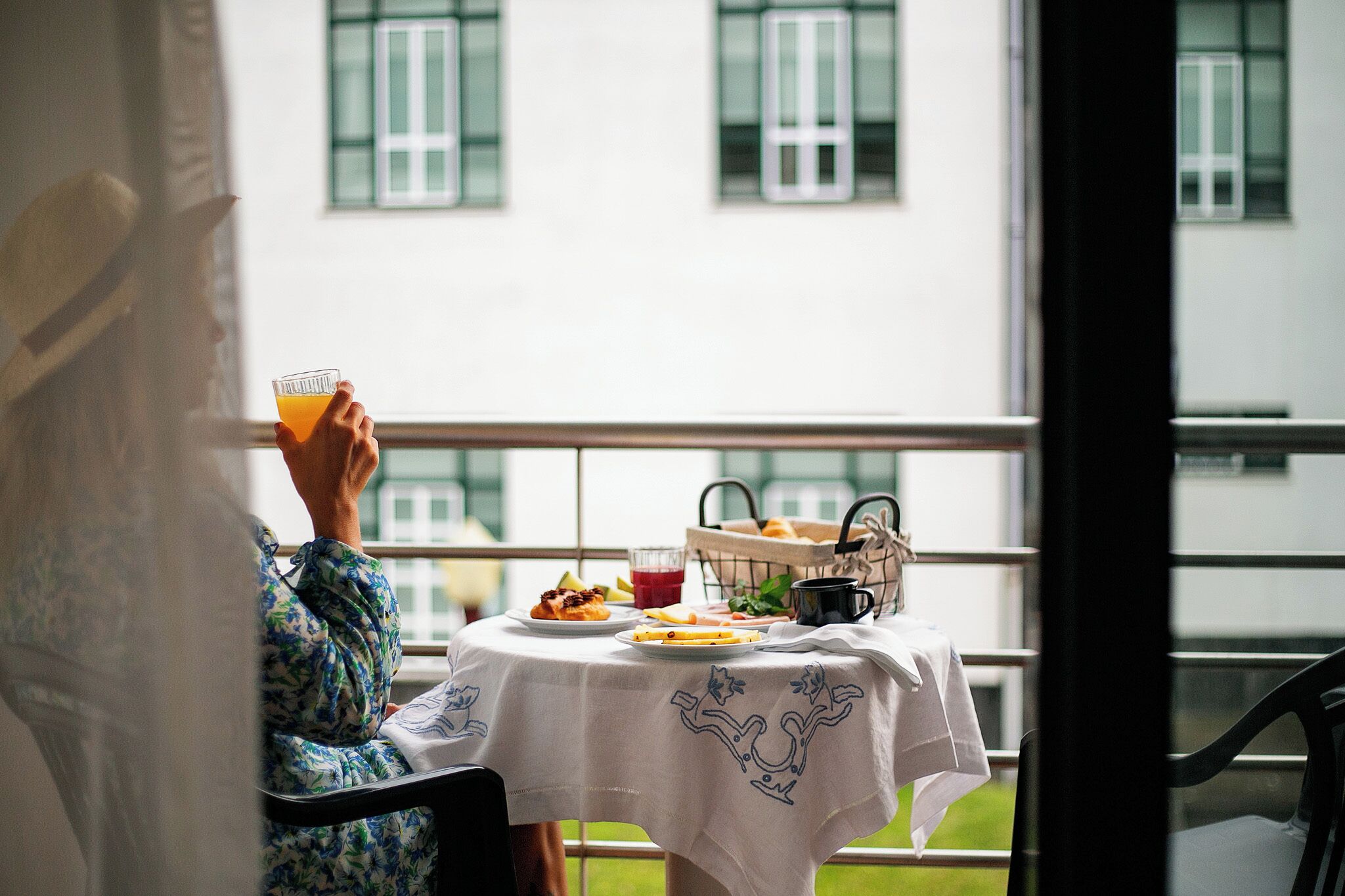 Una persona sentada a una mesa con una bebida, una cesta de pasteles y un plato de comida.