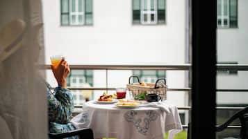 Una persona sentada a una mesa con una bebida, una cesta de pasteles y un plato de comida.